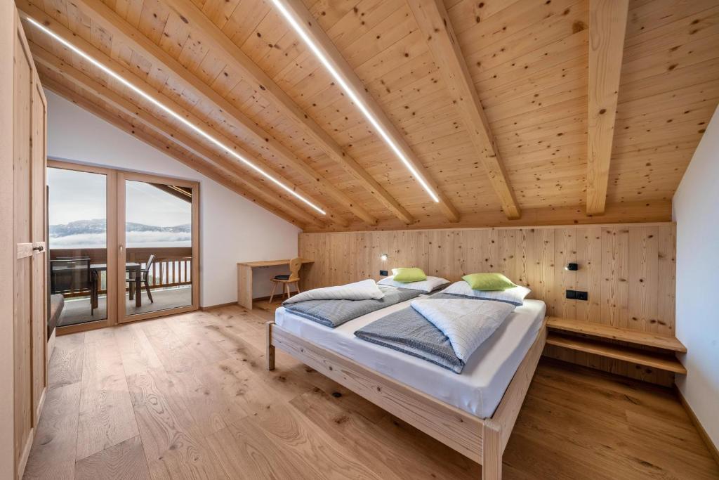 a bedroom with a bed and a wooden ceiling at Parliflhof Apt Laugenblick in Meltina