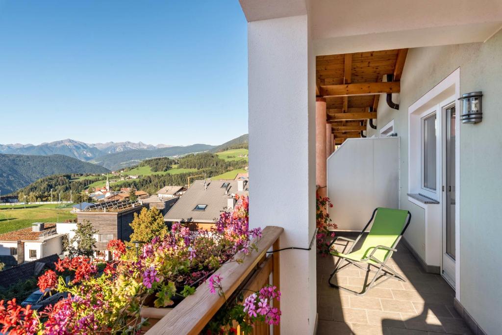a balcony with flowers and a green chair at Residence Diana Apartment 301 in Terento
