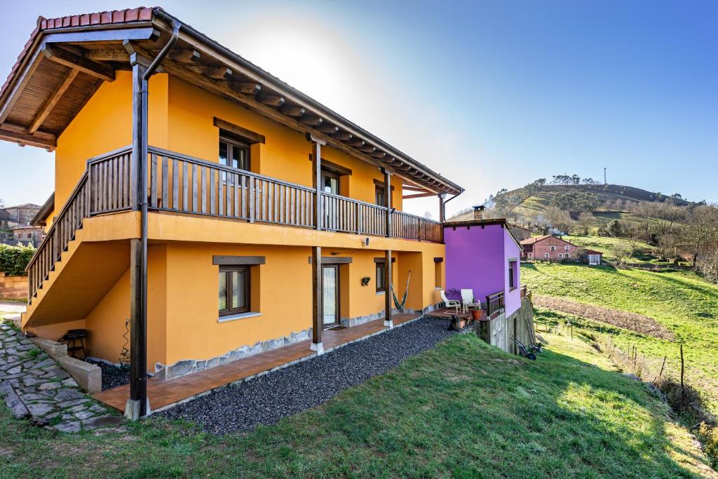 a yellow house with a balcony on a hill at Picuastur in Cangas de Onís