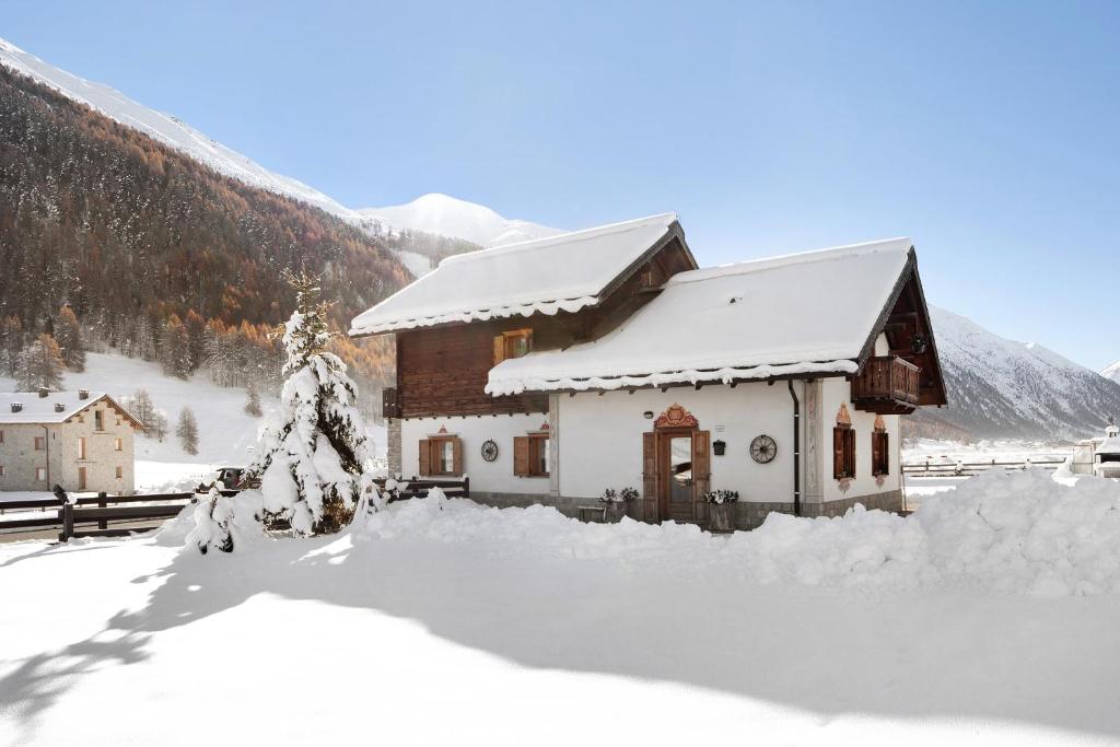 a house covered in snow in front of a mountain at Baita sulle Alpi Livigno in Livigno