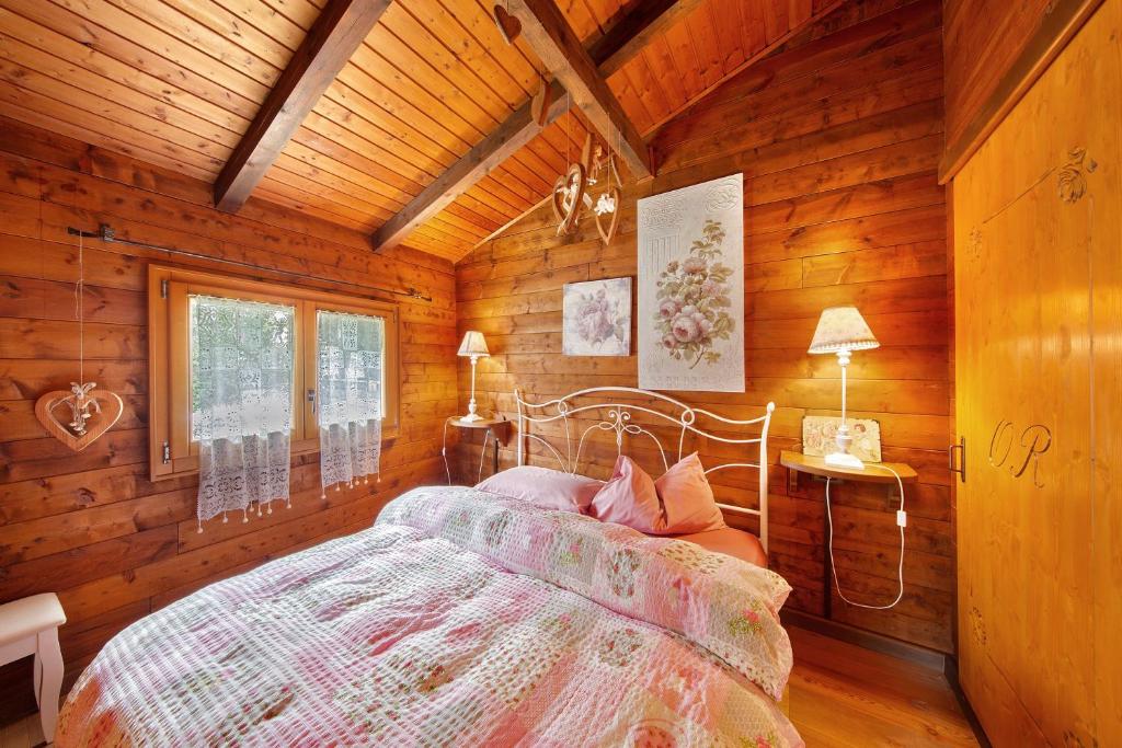 a bedroom with a bed in a wooden cabin at Orserose Chalet 4 Al Vant in Forno di Zoldo