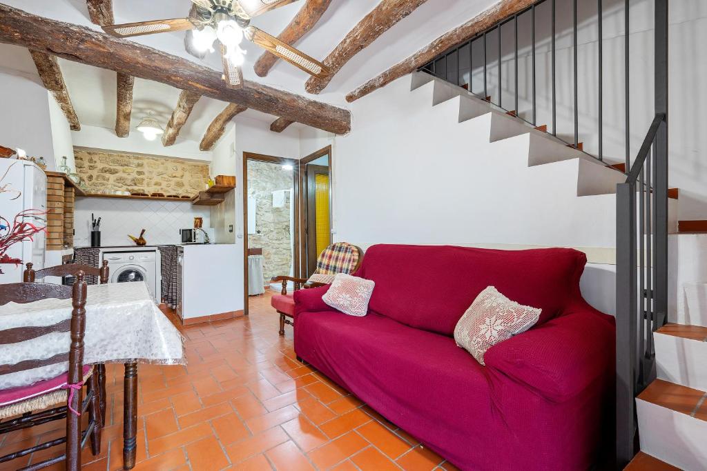 a living room with a red couch and a kitchen at Ca la Llum in Tivissa