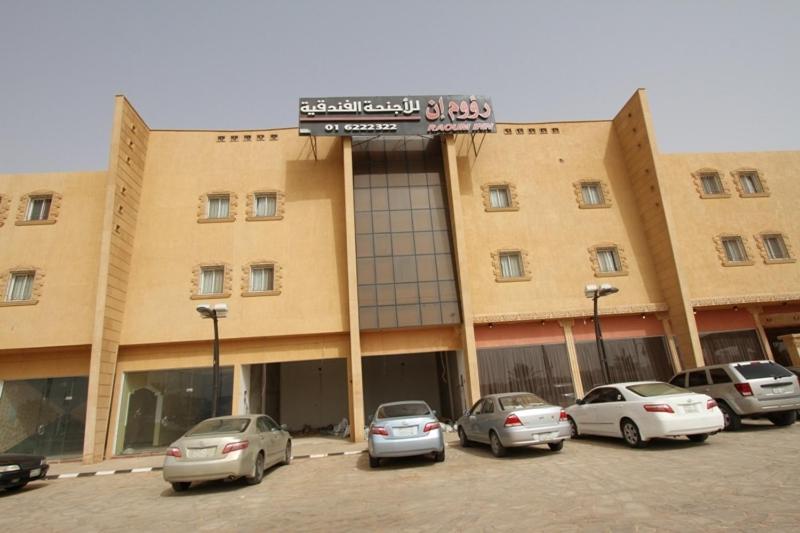 a large building with cars parked in a parking lot at Raoum Inn Shaqra in Shaqra