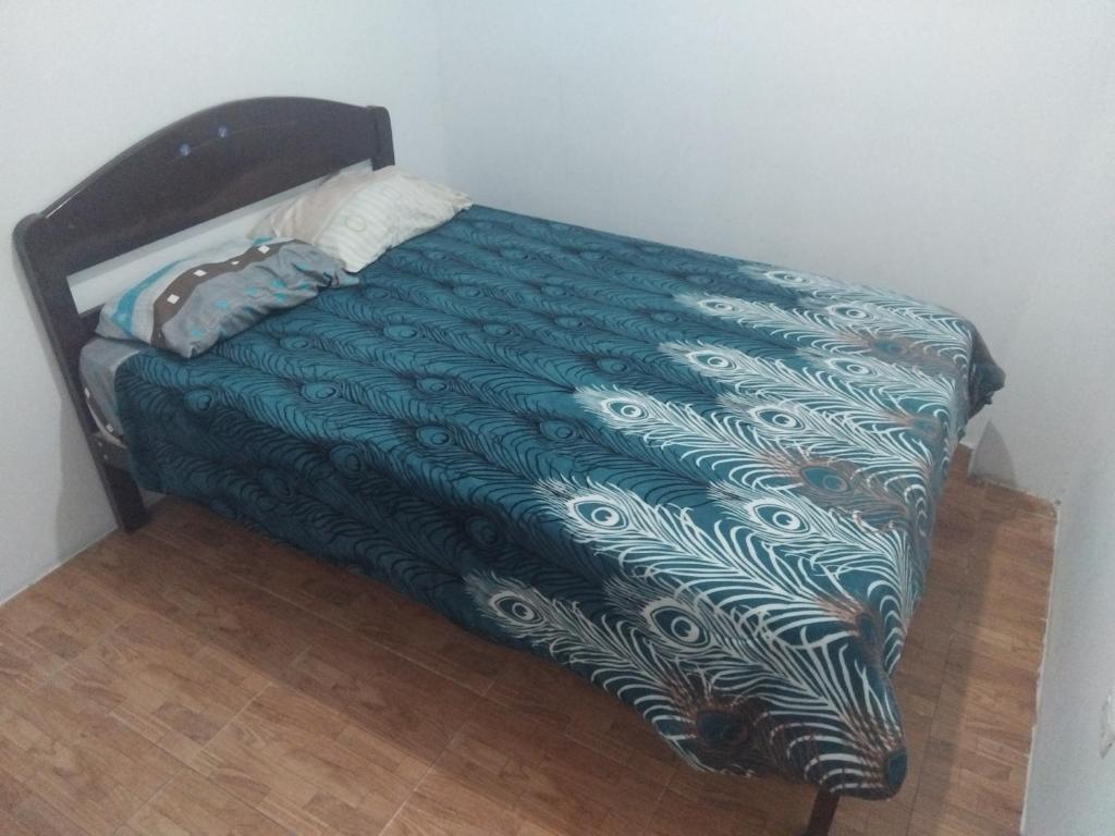 a bed with a green comforter on a wooden floor at Casa de huespedes en el centro in Cajamarca
