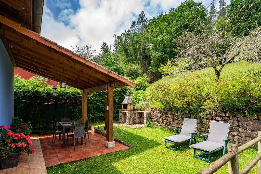 a patio with chairs and a table and a stone wall at La Pumarada in Villaviciosa