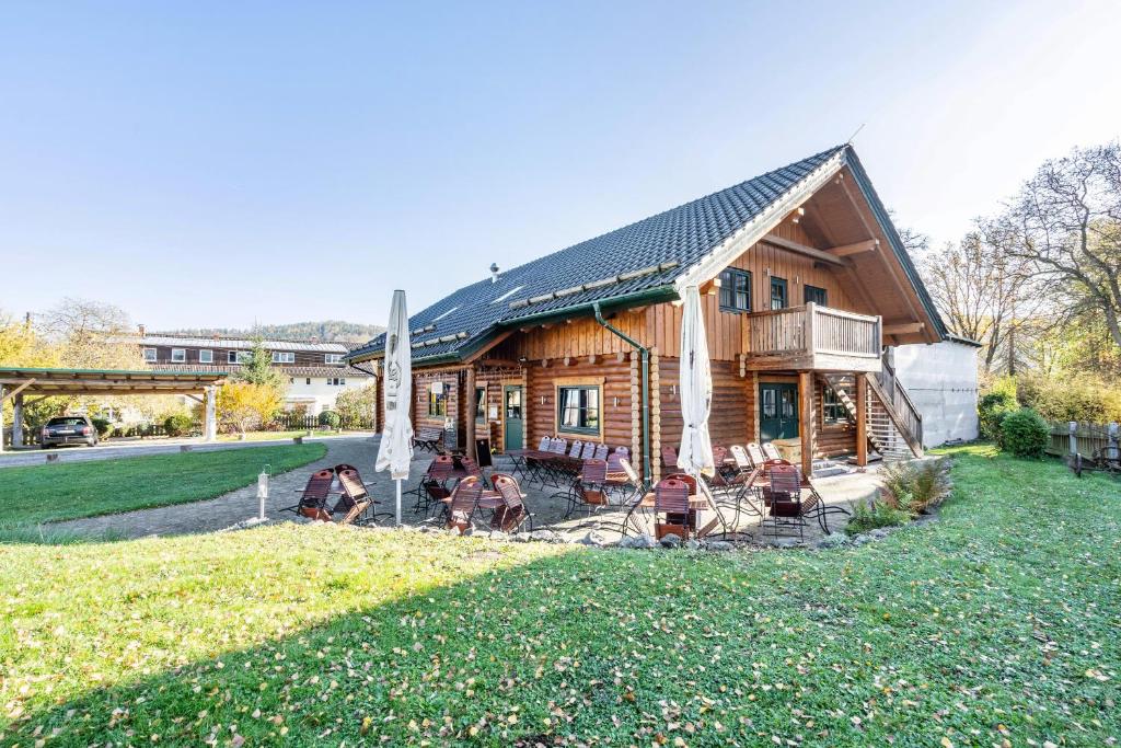 a log cabin with people sitting in chairs in the yard at Blockhaus - Ferienwohnung Sunset in Erdmannsdorf