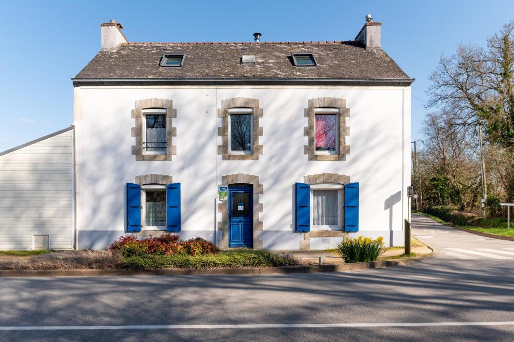 a white house with blue shutters on a street at Kervalou in Sainte Anne d'Auray