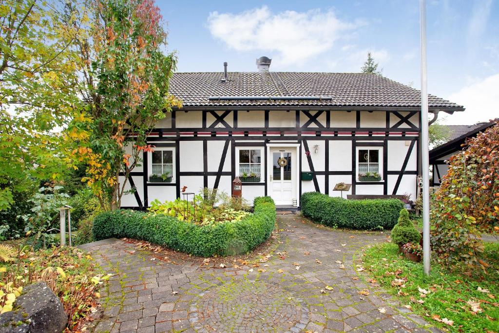 a white and black house with a garden in front of it at Ferienwohnung Rotdorn in Schmallenberg
