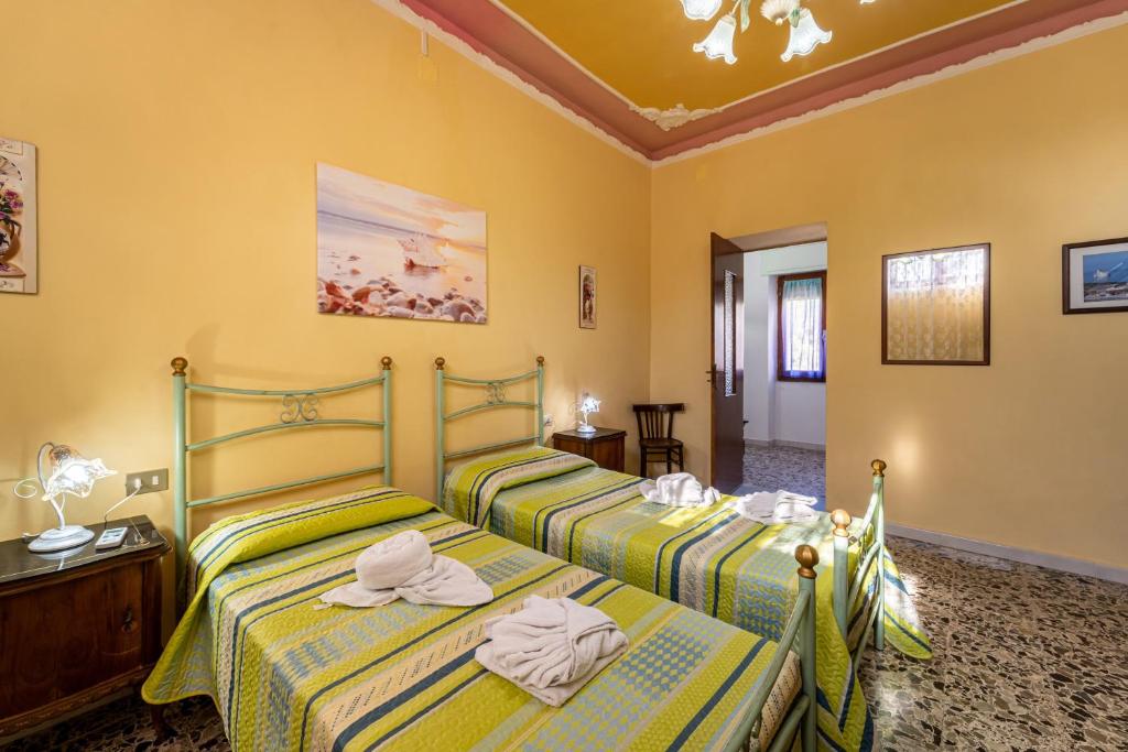 two beds in a room with yellow walls at Casa Margherita in Nebida