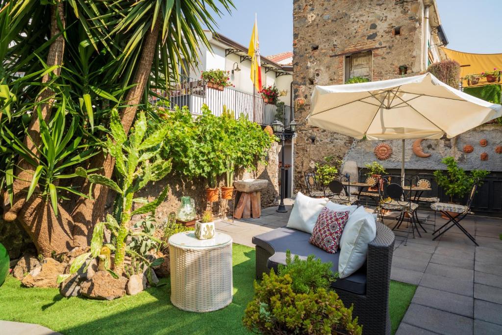 a patio with a couch and an umbrella at A Ugghia in Fiumefreddo di Sicilia