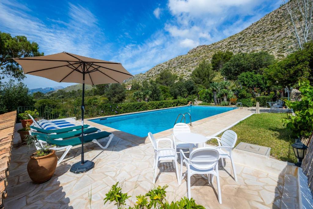 a patio with chairs and an umbrella next to a swimming pool at Villa Piedra in Pollença