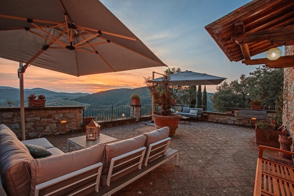 a patio with a couch and an umbrella at Podere Erbolino in Gaiole in Chianti