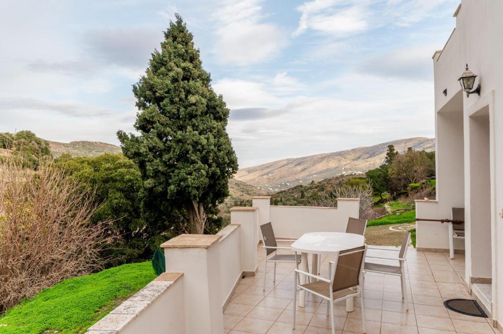 a patio with a table and chairs and a tree at Moraki Apartment 1 Andros in Korthi