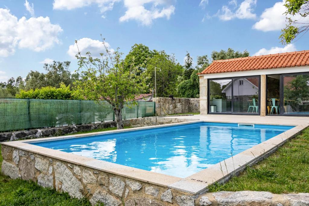 a swimming pool with a stone retaining wall next to a house at Casa do Mestre T2 in Vila de Punhe