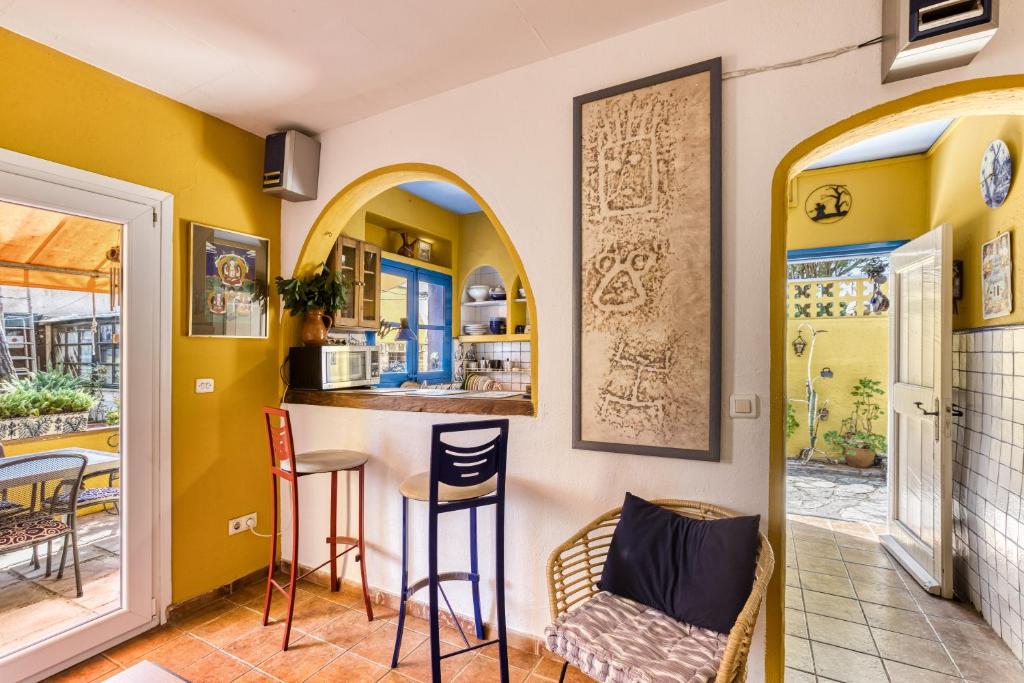 a kitchen with yellow walls and a bar with stools at Casa en urb Cala Montgó in L'Escala