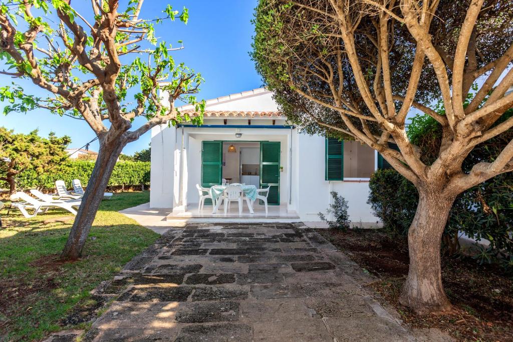 a white house with a patio and trees at Villa Goyo in Cala en Bosc