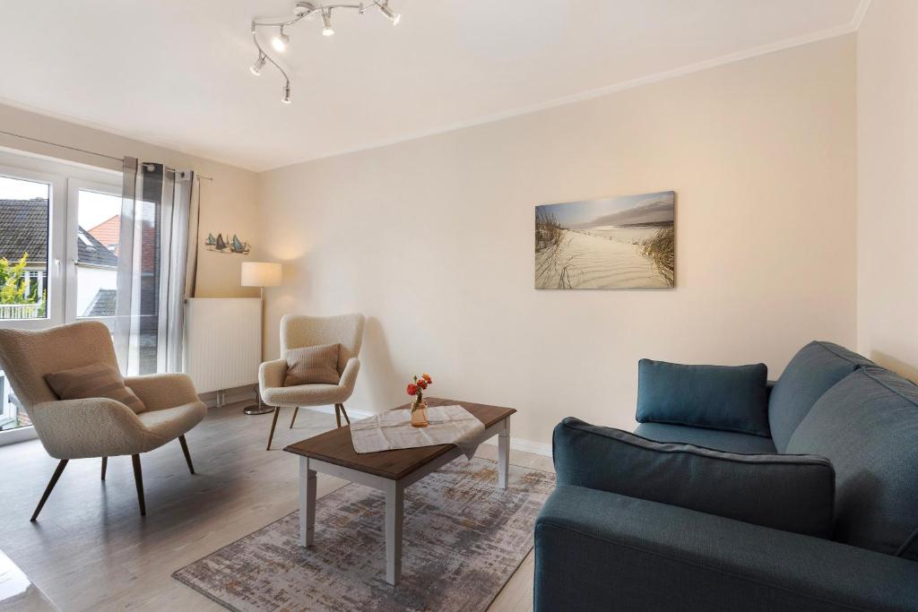 a living room with a blue couch and chairs at Sabines Ferienwohnung 2 in Glückstadt