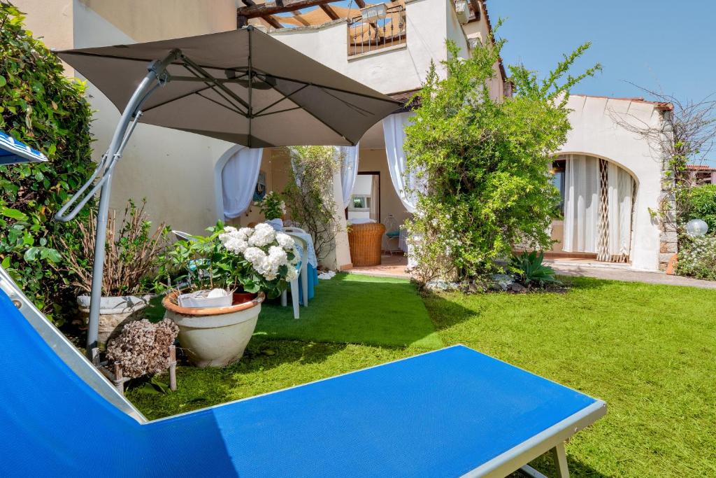 a blue table in a garden with an umbrella at Il Giardino di Viola in Porto Ottiolu
