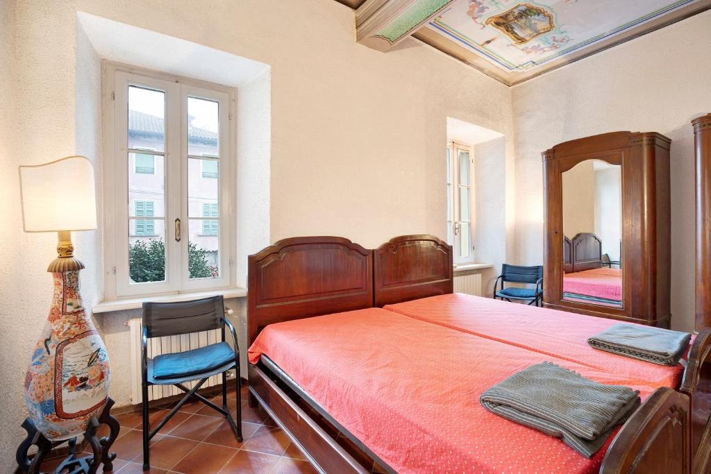 a bedroom with a bed and two chairs and a mirror at in Villa Belli in Miasino