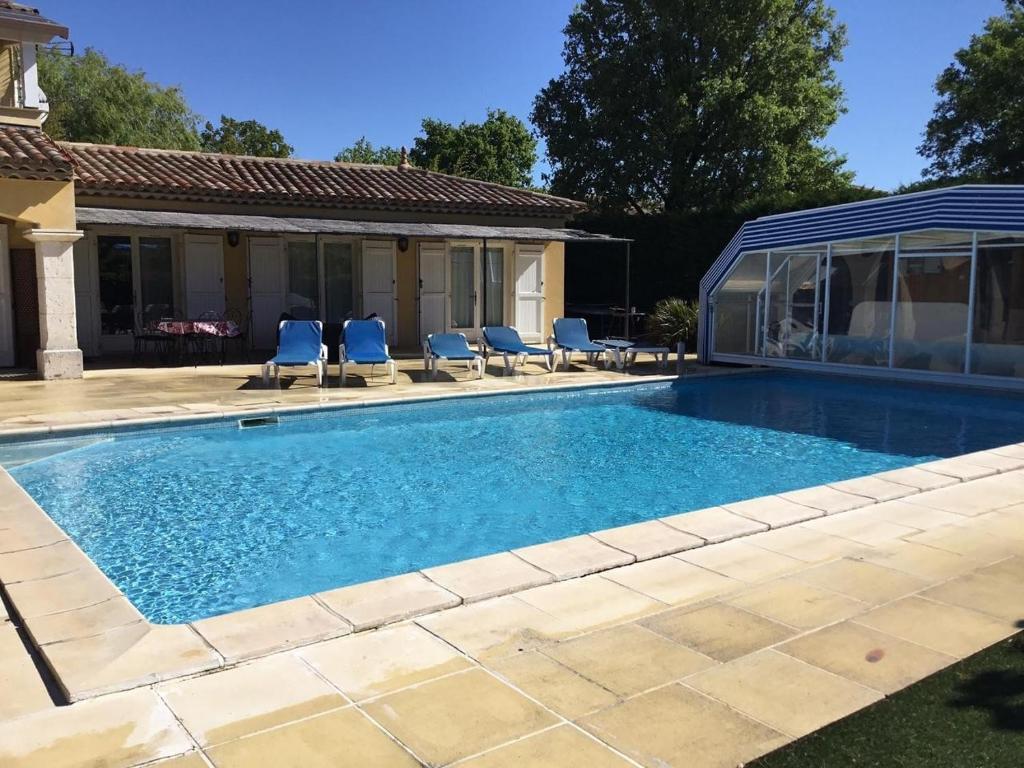 a swimming pool with chairs and a house at Maison avec Piscine in Tourrettes