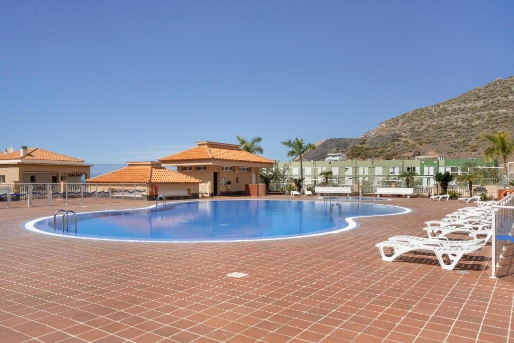 a swimming pool in a resort with chairs and buildings at Chasna Sunset in Adeje