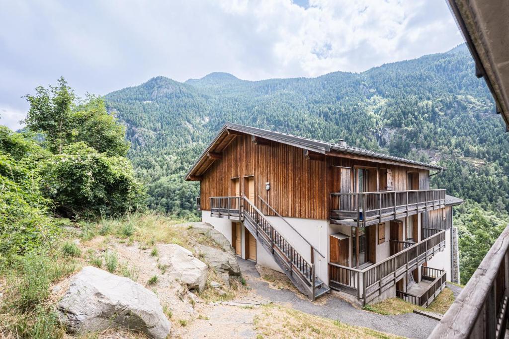 a house on a hill with mountains in the background at Appartement spa fleures d'Orelle in Orelle