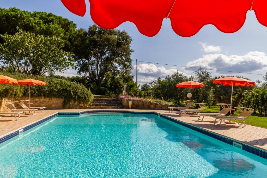 a swimming pool with two umbrellas and chairs and a pool at Il Cancellone - Grillo in Montiano
