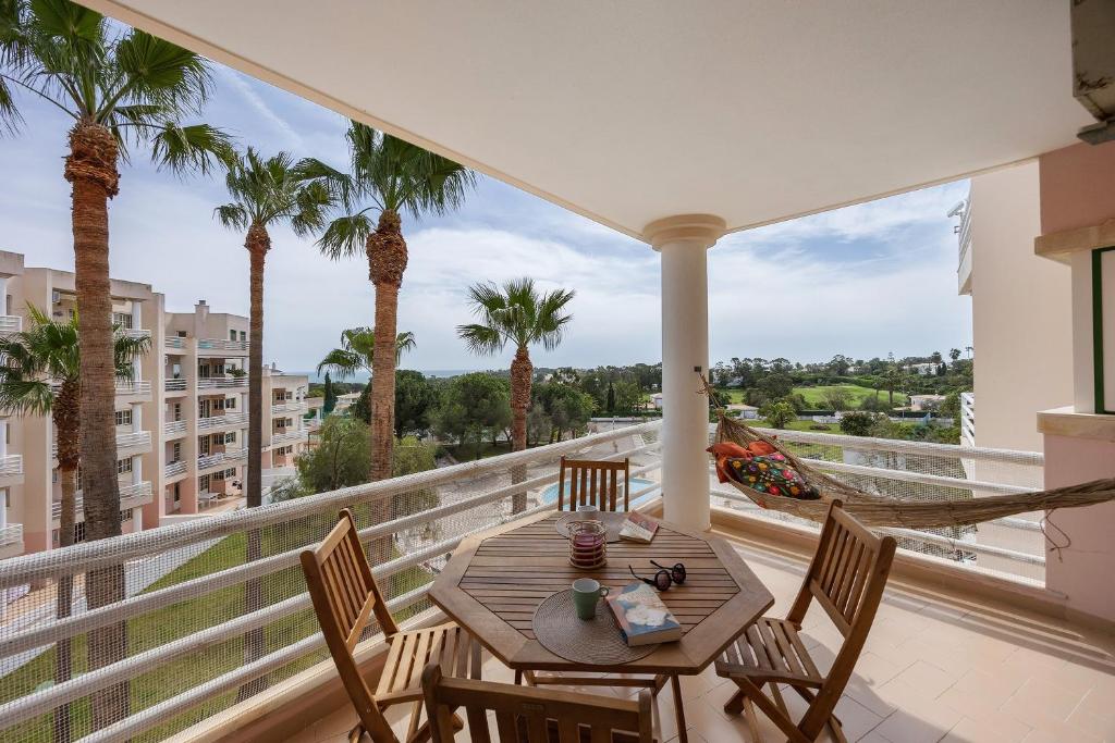 a balcony with a table and chairs and palm trees at Sol do Atlântico in Portimão