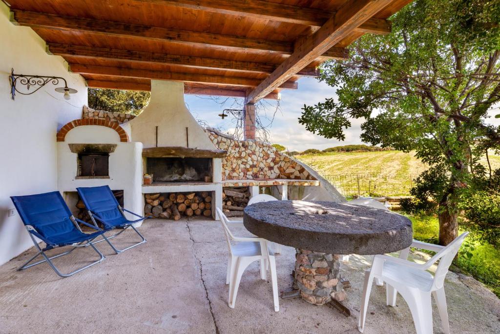 a patio with a table and chairs and a stone oven at Villa due Archi in S'archittu Cuglieri