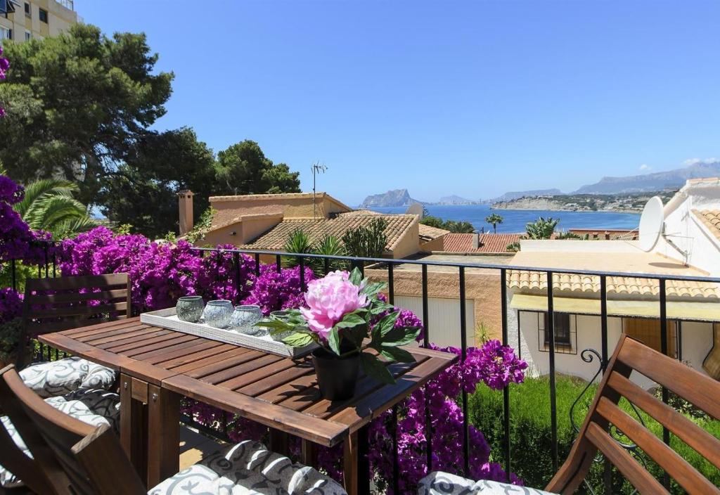a wooden table on a balcony with purple flowers at Vista Bahía in Moraira