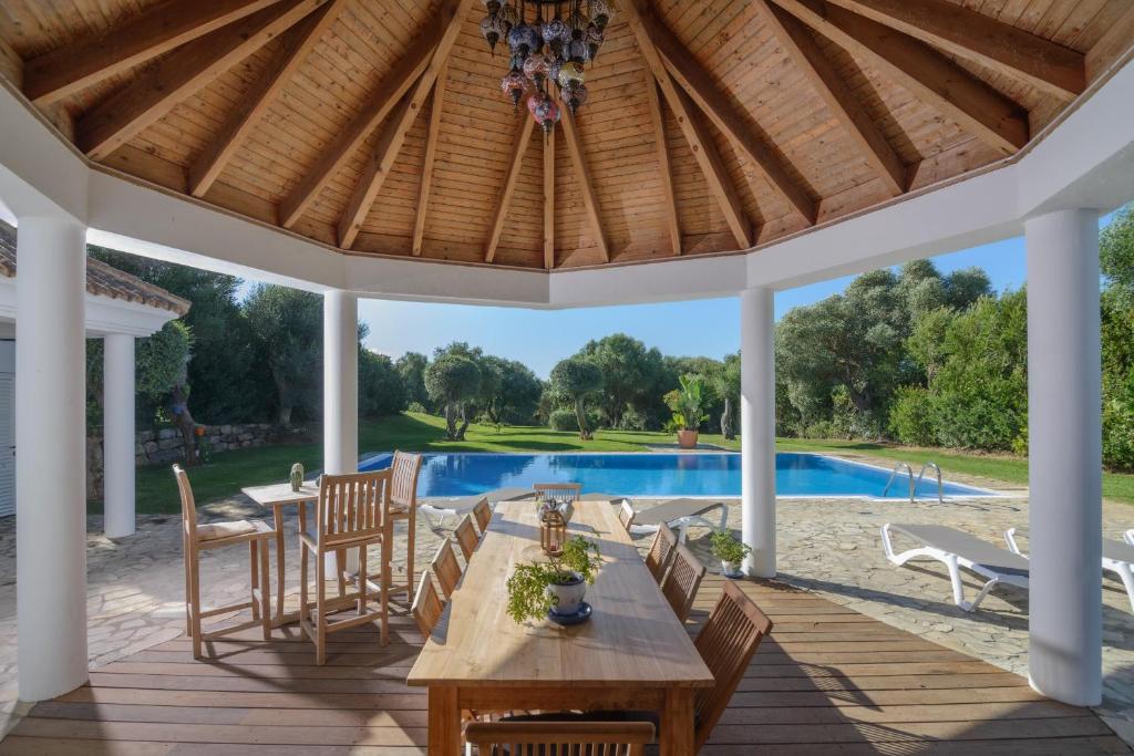 a pavilion with a table and chairs and a pool at Villa Lara in Benalup Casas Viejas