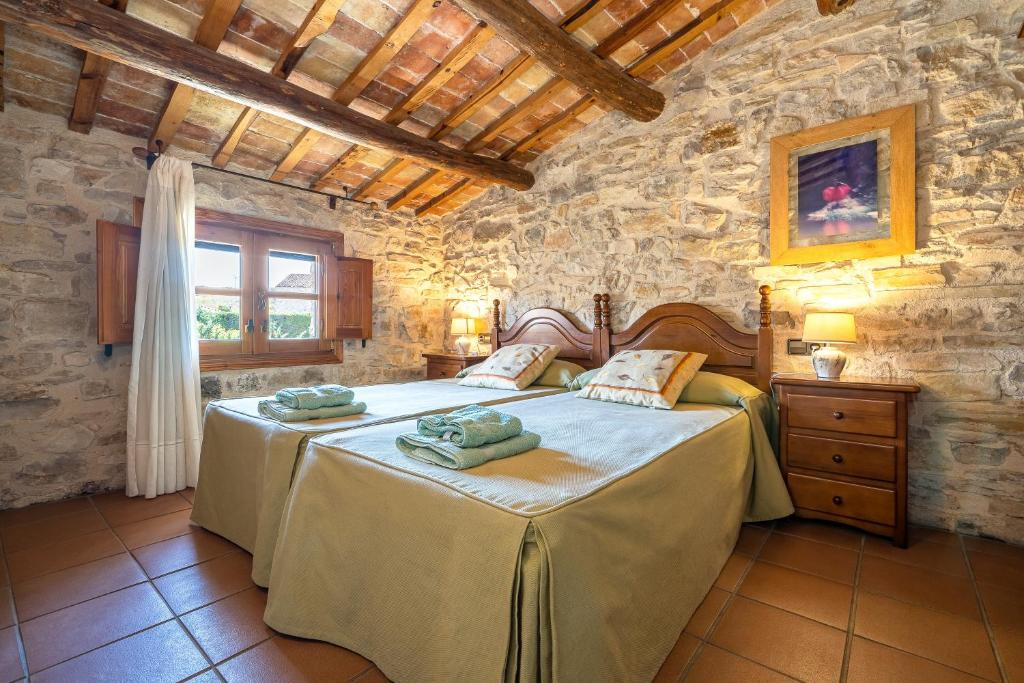 a bedroom with two beds and a stone wall at El Clos 3 in Conesa
