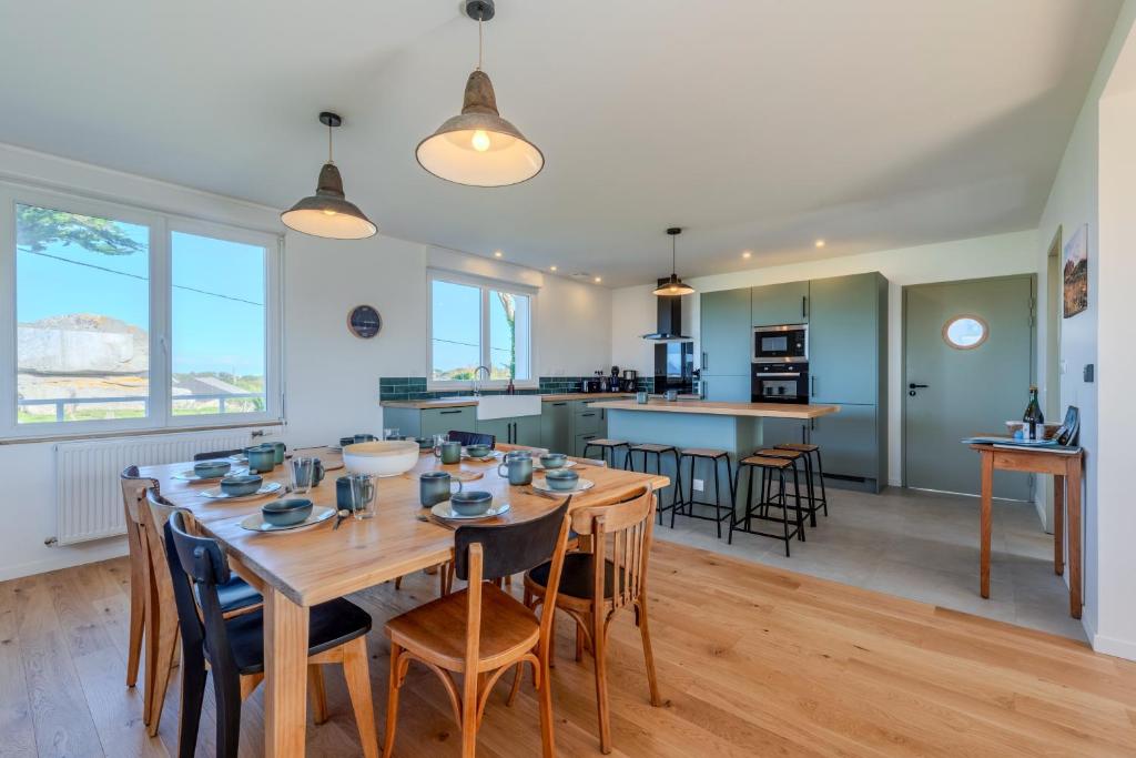 a kitchen and dining room with a wooden table and chairs at Maison Stoubenn in Kerlouan