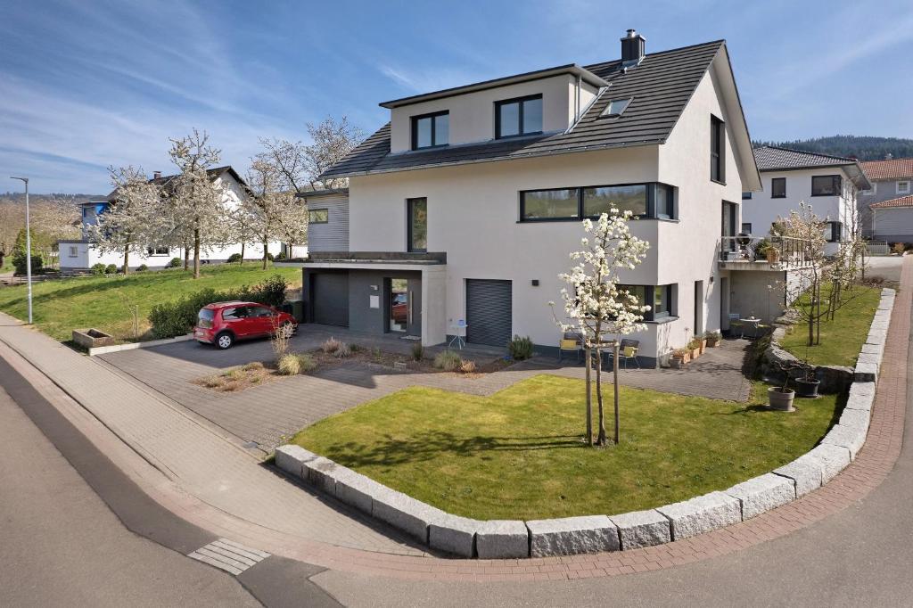 a white house with a red car parked in the driveway at Kölsch-Marie in Durbach