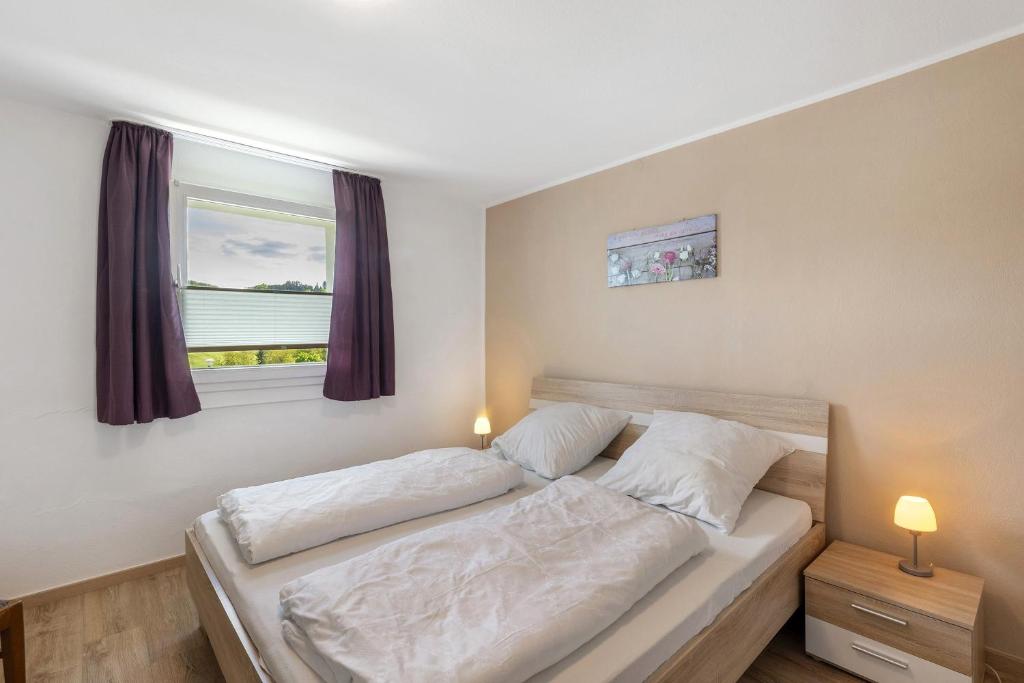 a bedroom with a bed with white sheets and a window at Ferienhaus Grobbel in Eslohe