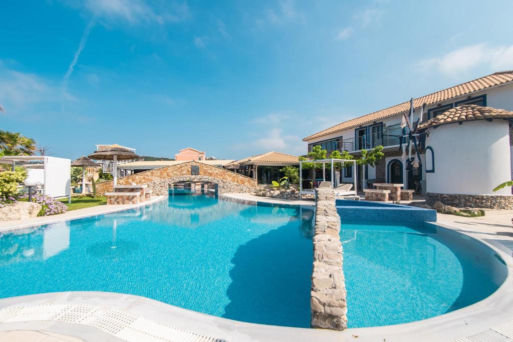 a swimming pool with blue water in front of a building at Mirage Arillas Maisonette B in Arillas