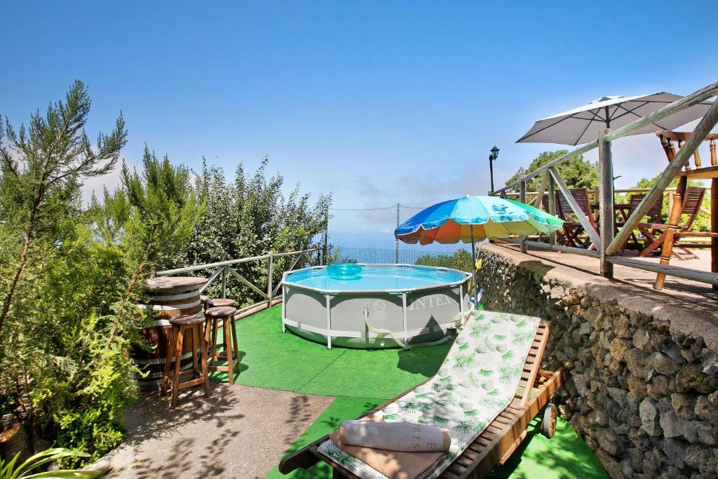 a swimming pool with an umbrella and chairs on a patio at Finca Las Carmenes in Icod de los Vinos