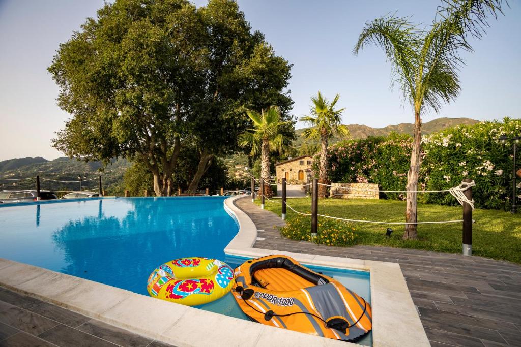 a swimming pool with two inflatable boats next to it at Arcaloro Resort in SantʼAngelo di Brolo
