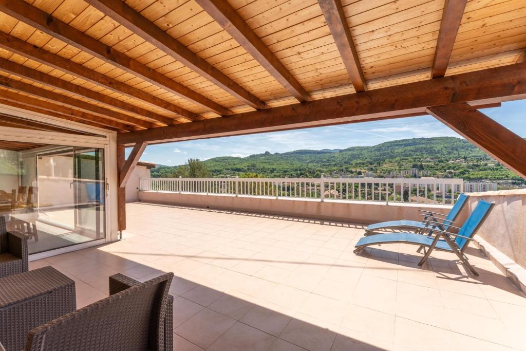 a patio with a wooden roof with chairs on it at Villa du soleil levant in Apt