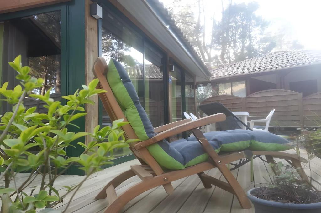 a rocking chair with pillows sitting on a porch at Maison, Piscine sous les pins in Moliets-et-Maa