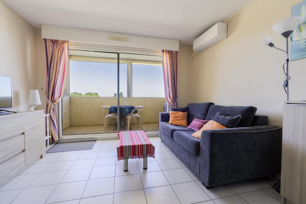 a living room with a couch and a table at Appartement clim piscine garage in Le Grau-du-Roi