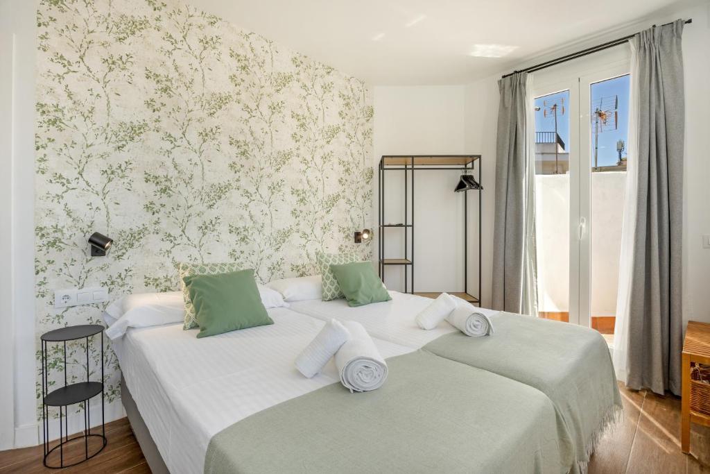 two beds in a bedroom with green and white wallpaper at Casa Milano 3 in Jerez de la Frontera