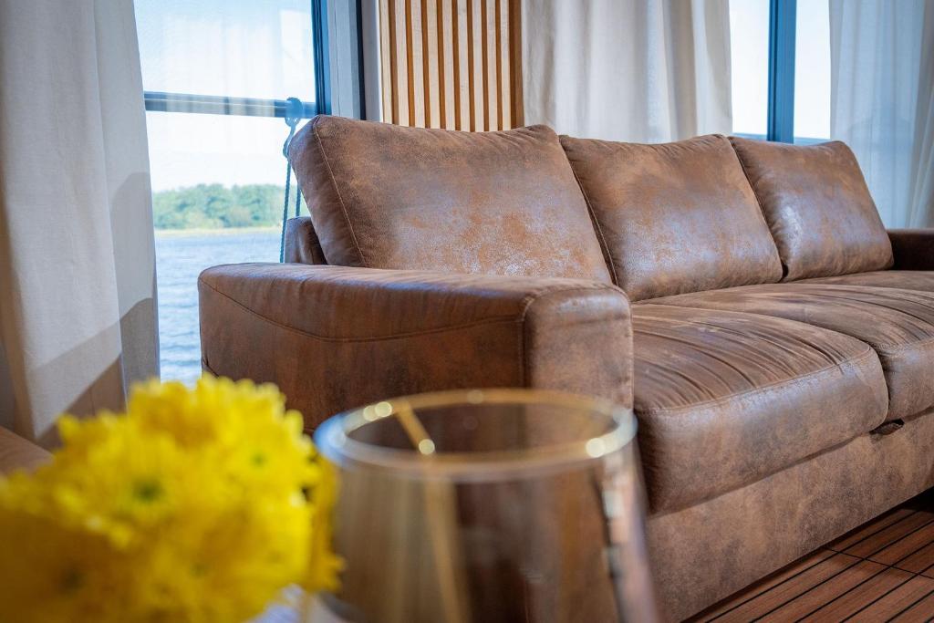 a brown couch in a living room with a table at Naturerlebnis Hausboot Frigga Woma in Fürstenberg