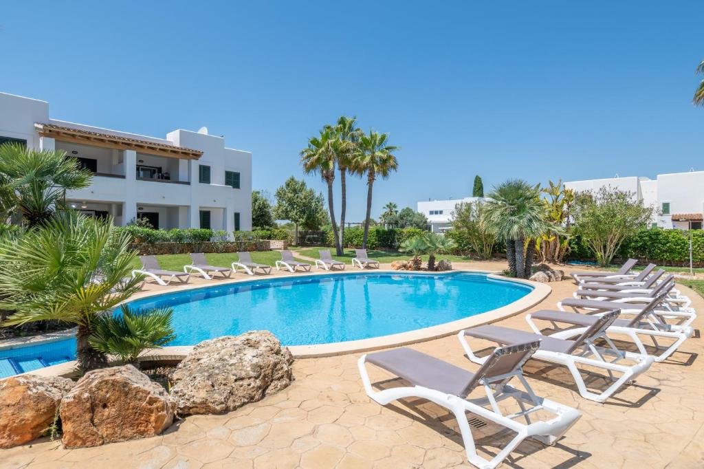 a swimming pool with lounge chairs and a resort at Cala Egos Villa - S'Estel in Cala d´Or