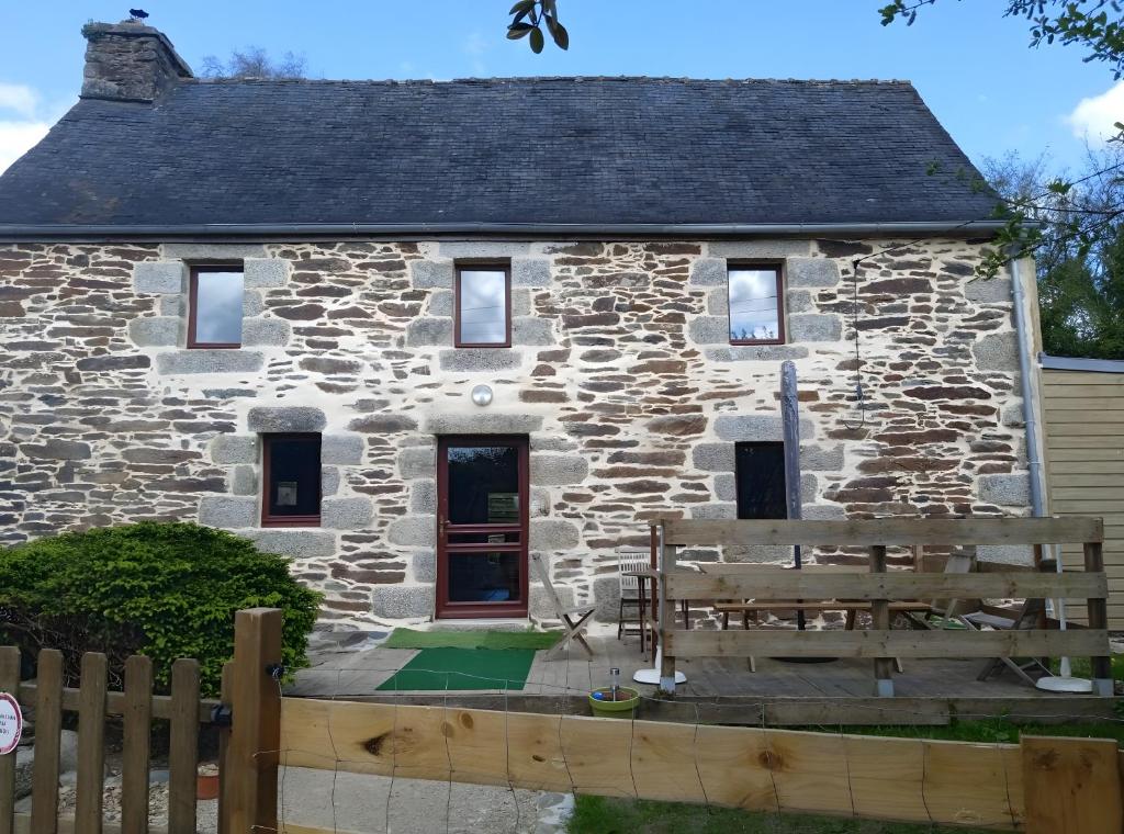 a stone house with a wooden fence in front of it at Gîte De Ty Louti in Plouyé