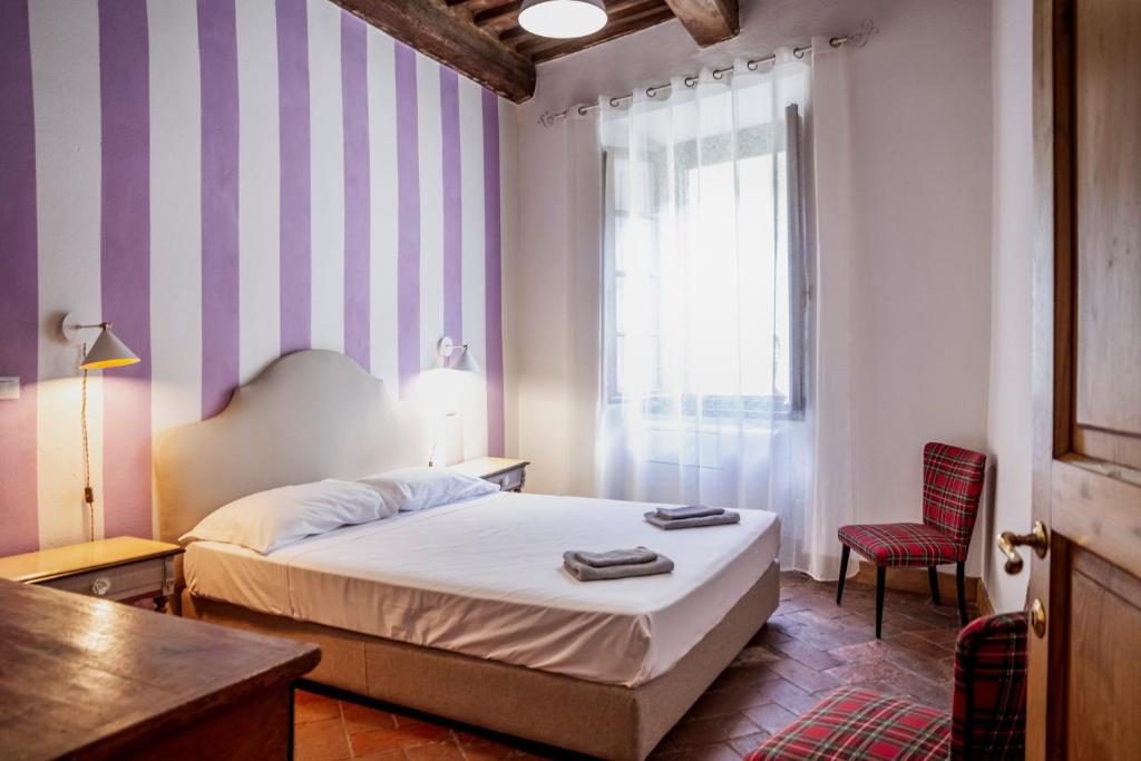 a bedroom with a bed and a chair and a window at Residenza Palazzo Ghio in Scansano