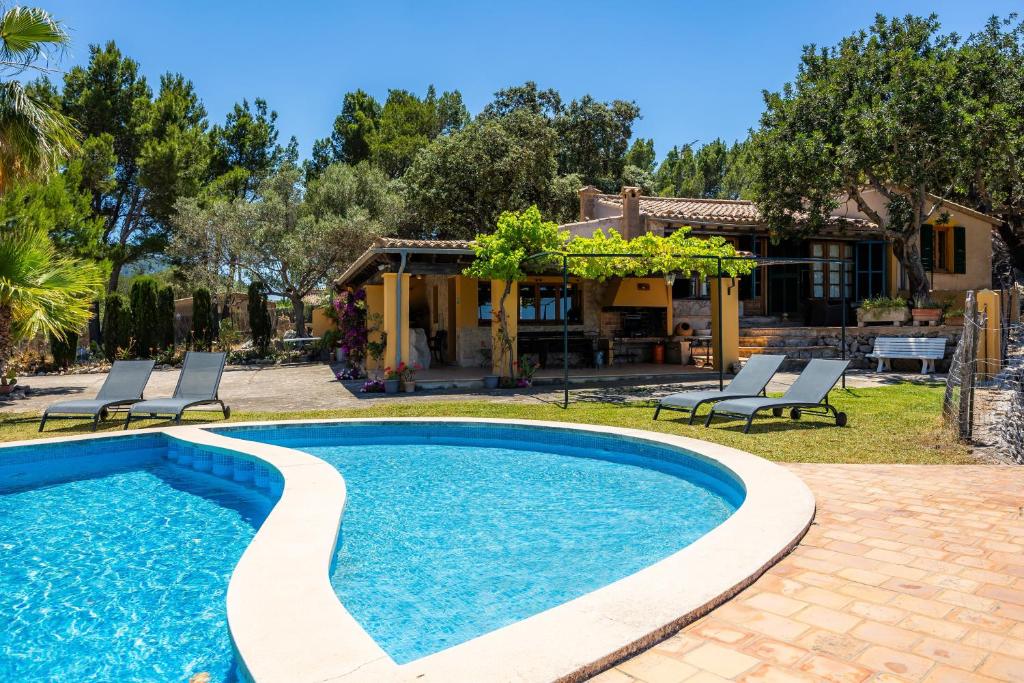 a pool with chairs and a house in the background at Tramuntana in Valldemossa