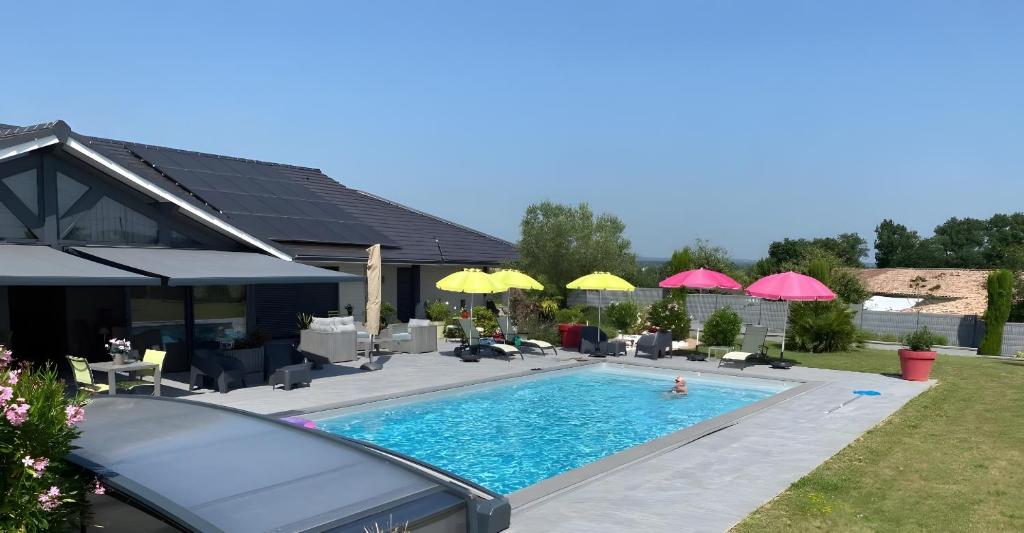 a swimming pool with umbrellas in a backyard at Loft Grand Confort Avec Piscine in Montalzat