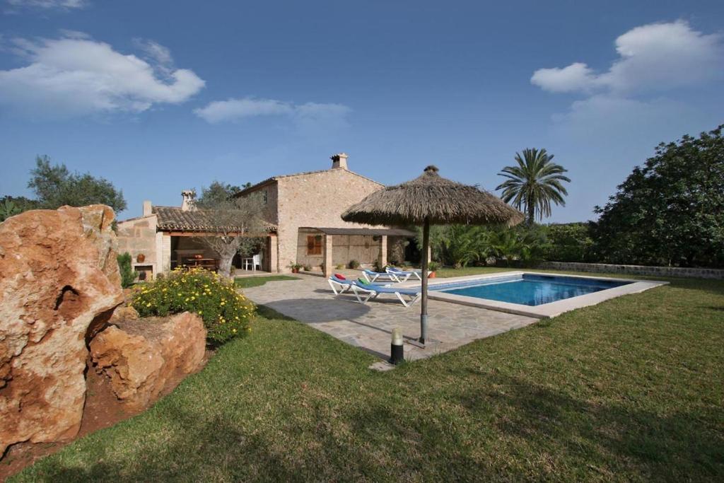 a house with a swimming pool and an umbrella at Butxaco in Pollença