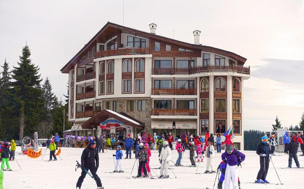 a group of people on skis in front of a building at Spider House Aparthotel in Pamporovo